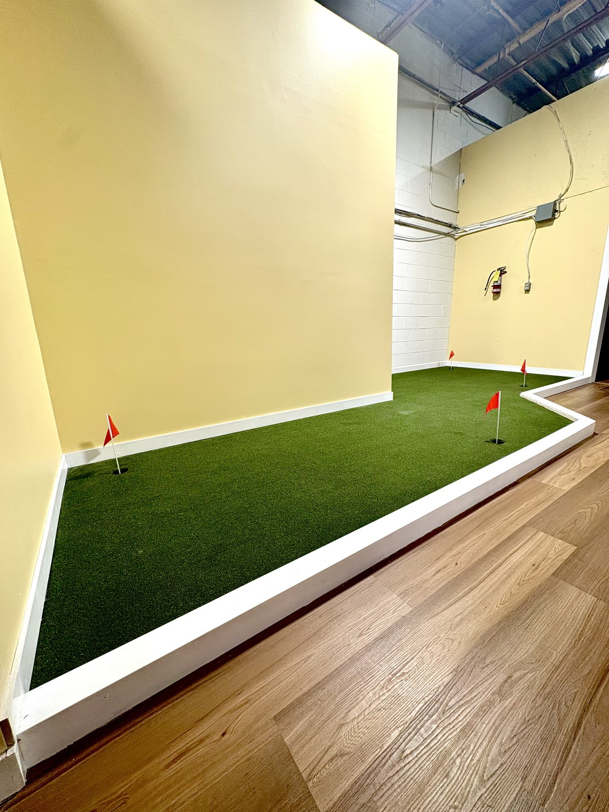 Indoor putting green with flag holes at The Bunkr